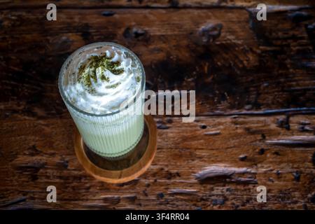Un verre de milkshake Matcha Green Tea nappé et garni d'un biscuit et de pâtes blanches. Banque D'Images