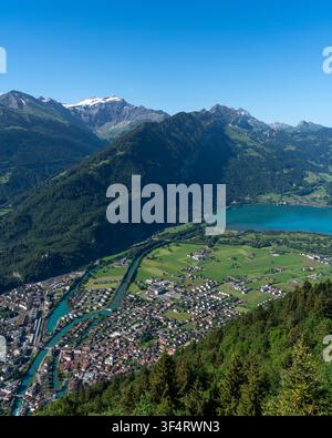 Vue du Harder Kulm sur la ville d'Unterseen, la rivière Aare et le lac de Thoune nichés parmi les Alpes suisses sous un ciel bleu clair. Unterseen, C Banque D'Images