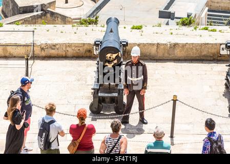 Valletta, Malte – 20 mai 2025 : Les visiteurs se rassemblent à la batterie historique de Saluting alors qu'une garde cérémonielle se tient à côté d'un canon restauré avant la trad Banque D'Images