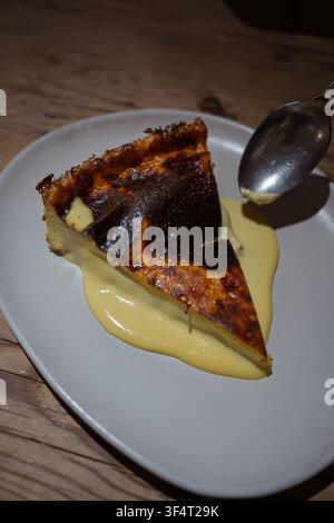 Cheesecake basque brûlé servi avec une crème vanille crémeuse dans une assiette Banque D'Images