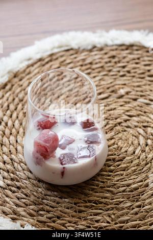 Close-up d'un café glacé crémeux avec des glaçons en jus de cerise congelé dans un verre transparent. Boisson rafraîchissante faite maison parfaite pour les chaudes journées d'été. Banque D'Images