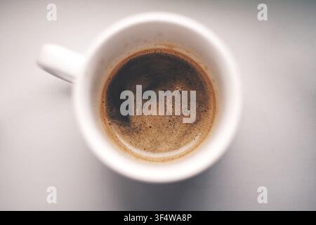 Une boisson café fraîchement préparée avec une mousse riche dans une tasse en céramique blanche, vue de dessus. Banque D'Images
