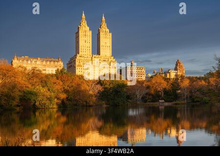 Feuillage automnal à Central Park reflété dans The Lake avec la ligne d'horizon de l'Upper West Side baignée d'une lumière matinale chaude, Manhattan, New York City, États-Unis Banque D'Images