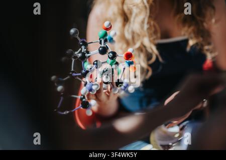 Étudiant tenant un modèle moléculaire coloré représentant l'étude de la chimie et l'éducation scientifique dans le laboratoire scolaire Banque D'Images