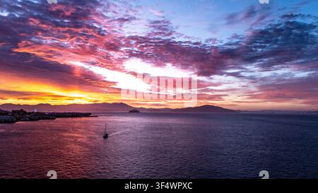 Vue aérienne d'un voilier dans la baie de San Francisco lors d'un coucher de soleil éclatant avec l'île d'Alcatraz au loin et la skyline de la ville de San Francisco, Californie Banque D'Images