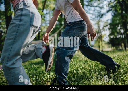 Amis adolescents courant et jouant ensemble dans un parc ensoleillé, vêtus de jeans décontractés et de baskets Banque D'Images