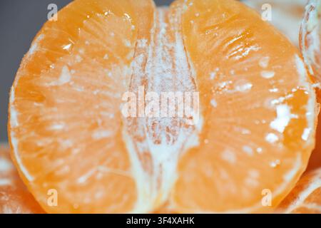 Photographie macro détaillée d'un segment de mandarine fraîchement pelé montrant des détails complexes de la pulpe, des gouttelettes d'humidité naturelles et un noyau blanc fibreux Banque D'Images