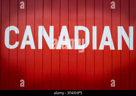 Photo en gros plan d'un fond en bois rouge avec le mot Canadian écrit dessus. Personne. Banque D'Images