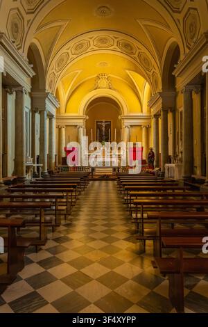 Intérieur d'église vide avec des rangées de bancs en bois menant à l'autel et au crucifix Banque D'Images