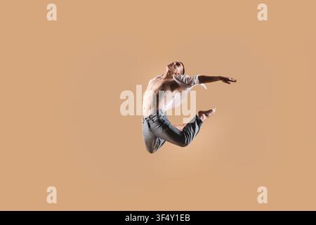 Danseur professionnel pratiquant des mouvements sur fond beige Banque D'Images