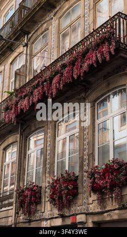 Fleurs roses en cascade sur les balcons en fer d'une façade carrelée d'azulejo, Porto, Portugal Banque D'Images