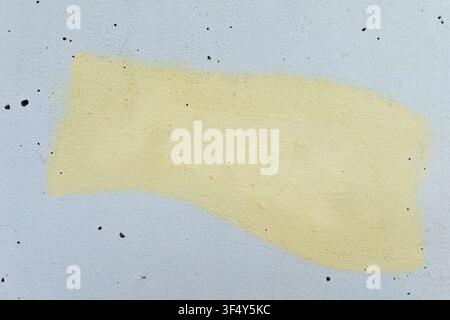 Fond mural grunge texturé avec une tache de peinture jaune pâle sur une surface blanche Banque D'Images