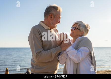 Couple senior mature embrassant profitant des loisirs en plein air marchant sur la plage. Vieux mari épouse embrassant avec tendresse amour appréciant le lien doux. Grand-mère grand-père ensemble. Moment familial amour Banque D'Images