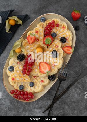 Composition de petit-déjeuner en hauteur mettant en vedette des crêpes et des gaufres maison garnies de baies fraîches et de fruits de saison Banque D'Images