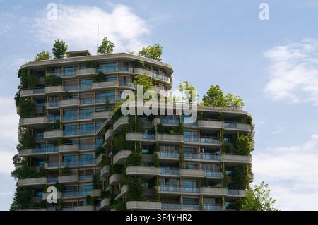 Vue en contre-plongée des étages supérieurs d'un gratte-ciel durable moderne comportant des jardins verticaux luxuriants, des arbres, intégrés à l'architecture Banque D'Images