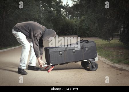 Homme en sweat à capuche noir organisant et préparant du matériel photographique professionnel en extérieur Banque D'Images