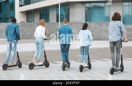 Groupe de jeunes adultes montant des scooters électriques dans un cadre urbain, non reconnaissables, concept de mode de vie Banque D'Images