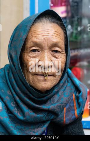 Kathmandu, Népal - 04 avril 2025 : Vue d'une femme âgée portant un foulard traditionnel à motifs et un anneau nasal en or orné de pierres colorées dans le Banque D'Images