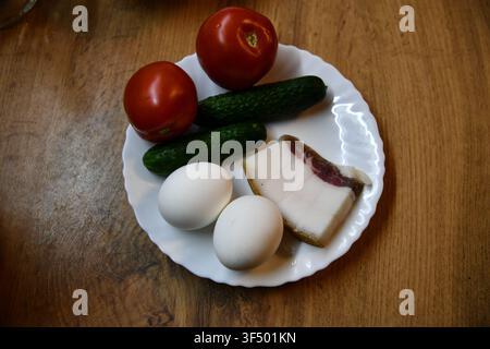 Petit-déjeuner anglais copieux comprenant des œufs, du bacon, des saucisses, des haricots, une tomate et du pain grillé, servi sur une table en bois Banque D'Images
