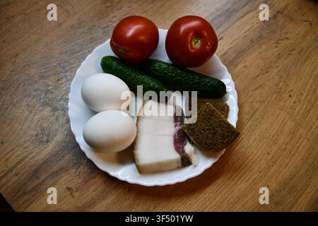 Petit-déjeuner anglais copieux comprenant des œufs, du bacon, des saucisses, des haricots, une tomate et du pain grillé, servi sur une table en bois Banque D'Images