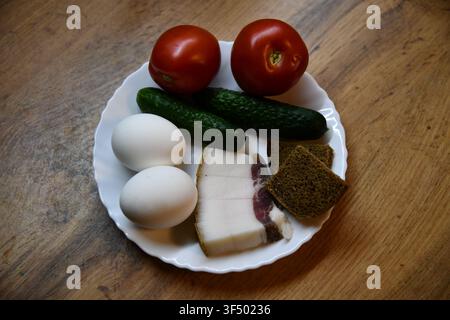 Petit-déjeuner anglais copieux comprenant des œufs, du bacon, des saucisses, des haricots, une tomate et du pain grillé, servi sur une table en bois Banque D'Images