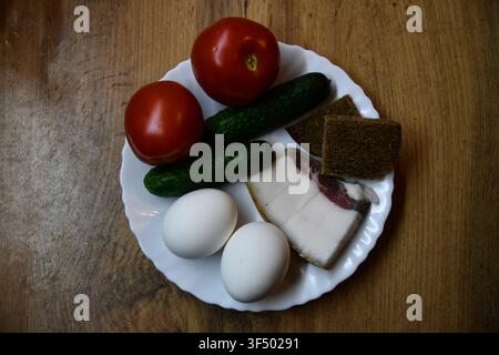 Petit-déjeuner anglais copieux comprenant des œufs, du bacon, des saucisses, des haricots, une tomate et du pain grillé, servi sur une table en bois Banque D'Images