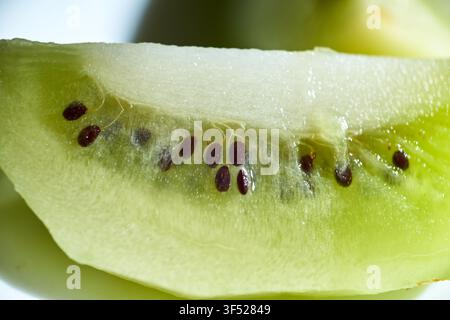 Photographie en gros plan d'une tranche de kiwi vert frais montrant la chair intérieure détaillée, les minuscules graines noires et la texture translucide Banque D'Images