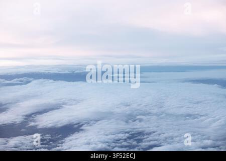 Une vue aérienne à couper le souffle capture des nuages blancs et moelleux s'étendant à l'infini en dessous, rencontrant un ciel bleu serein à l'horizon. Le paysage nuageux crée un rêveur Banque D'Images