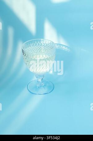 Cocktail pétillant élégant dans un verre en cristal avec fond lumineux bleu festif – Concept de célébration du Nouvel An Banque D'Images