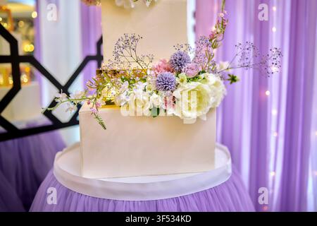 Gâteau de mariage blanc à trois étages élégant avec fleurs fraîches – Dessert de réception de mariage de luxe Banque D'Images
