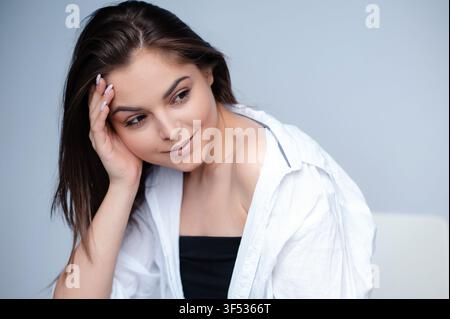 Femme brune en pose pensive dans le studio Banque D'Images