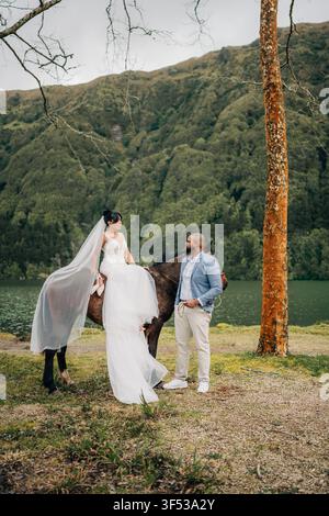 La mariée est assise sur un cheval avec son mari à proximité Banque D'Images