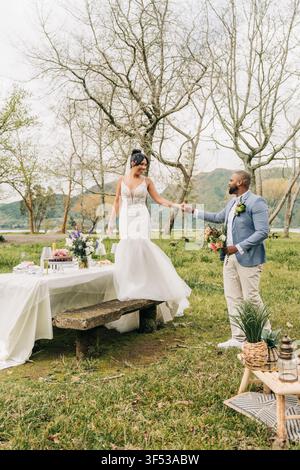 Couple heureux se tenant la main lors d'une célébration de mariage rustique Banque D'Images