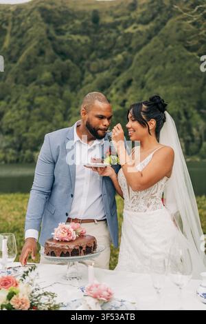 Une mariée heureuse donne une bouchée de gâteau de mariage à son marié Banque D'Images