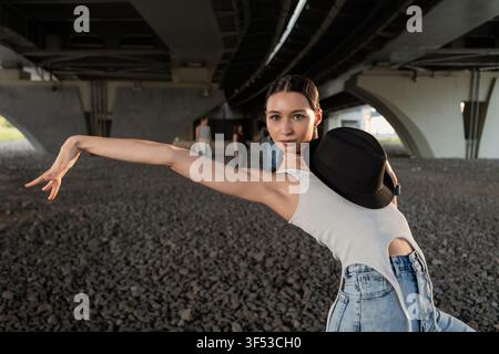 Femme élégante prenant une pose de danse dynamique sous un pont Banque D'Images