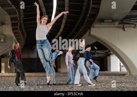 Jeune femme heureuse sautant avec des amis sous un pont Banque D'Images