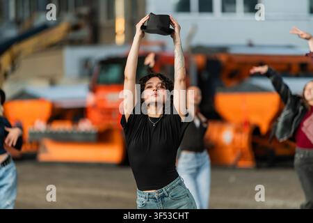 Jeune femme dansant dans la rue tenant un chapeau fedora Banque D'Images