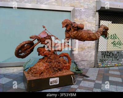 Artiste de rue jouant le rôle d'une statue vivante avec un tour de lévitation spectaculaire sur une moto, tous deux couverts de boue, à Madrid, en Espagne. Banque D'Images
