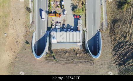 Vue aérienne de dessus des portails d'entrée de deux tunnels autoroutiers avec cour de maintenance et véhicules garés en Grèce pour le sto d'infrastructure de transport Banque D'Images