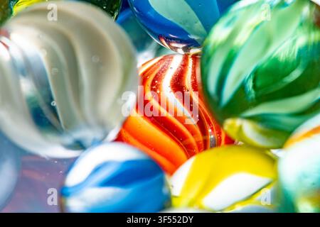 Billes en verre montrant des tourbillons et des reflets vibrants en vue macro Banque D'Images