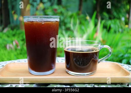 Café glacé et café chaud à la vapeur servis sur une table de jardin Banque D'Images
