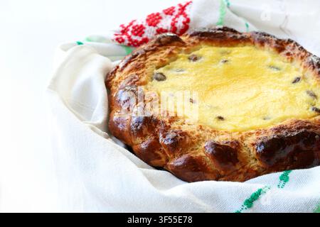 Pain sucré traditionnel de Pâques garni de fromage blanc et de raisins secs, enveloppé dans une serviette brodée. Photo d’archive pour des concepts de pâtisserie et de fête. Banque D'Images