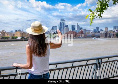 Vue arrière d'une touriste prenant des photos de la skyline de Londres, Angleterre, pendant son tour de ville Banque D'Images