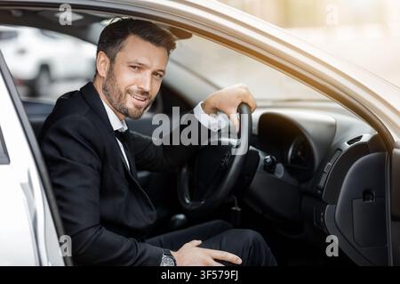 Un jeune entrepreneur heureux assis en voiture, en voiture pour se rendre à l'aéroport Banque D'Images