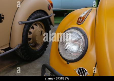 Une photographie en gros plan du phare et de l'aile avant d'une automobile jaune de style Coccinelle vintage. L'image met en valeur le design automobile classique et Banque D'Images