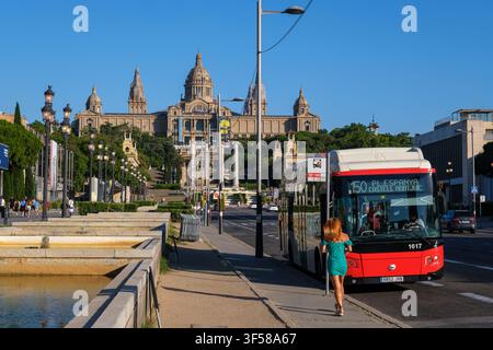 Barcelone, Espagne - 3 juillet 2026 : Bus de transport public TMB rouge et blanc dans la rue à Barcelone avec le Musée National d'Art de Catalogne visible en arrière-plan Banque D'Images