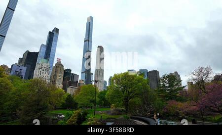 NEW YORK, NY, ÉTATS-UNIS - 10 MAI 2024 : Vue en contre-plongée regardant vers le haut des gratte-ciel résidentiels modernes dominant la végétation verte du parc à Central Park Banque D'Images