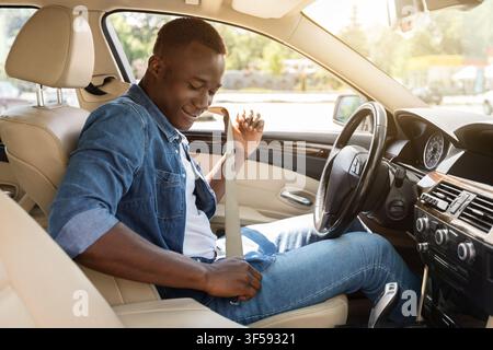 Positif noir homme attacher la ceinture de sécurité de voiture Banque D'Images