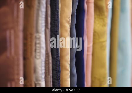 Des rouleaux de tissu colorés sont suspendus dans une boutique à vendre Banque D'Images