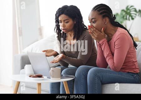 Une petite amie noire confuse assise devant un ordinateur portable Banque D'Images